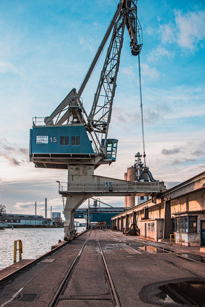 pexels-photo-16470124 Vertical shot of a harbor crane by industrial warehouses during the day.